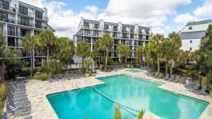 a swimming pool in front of a large apartment building at 123D Shipwatch by AvantStay Beach Access Pool in Isle of Palms