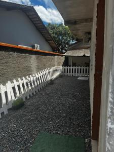 a white picket fence in front of a house at Park e Mar Studio quarto 1 in Penha