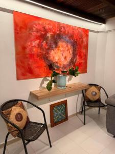 a table with two chairs and a painting on the wall at Cabaña frente al Río-Curití-San Gil in Curití