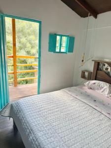 a bedroom with a bed and a large window at Cabaña frente al Río-Curití-San Gil in Curití