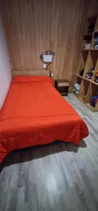 a bedroom with a red bed in a room with shelves at Casa mirador de volcanes, 6 personas in Llanquihue