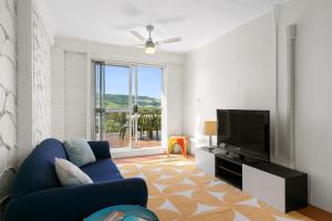 een woonkamer met een blauwe bank en een flatscreen-tv bij Ziggy's Place in Gerringong