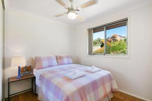 een witte slaapkamer met een bed en een raam bij Ziggy's Place in Gerringong