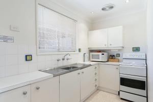 een witte keuken met een spoelbak en een magnetron bij Ziggy's Place in Gerringong +3 foto's