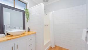 EpsomNouveau Home的一间白色浴室，配有洗手池和镜子。