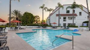 a swimming pool with tables and chairs in front of a building at Encantamar Escape by AvantStay Prime Location Community Amenities in Dana Point