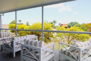 Pet Friendly Sleeps 8 Bowen Holiday House في بوين: بلكونه ذات كراسي بيضاء واطلاله على اشجار