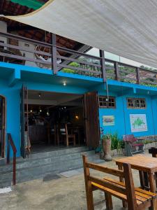 a blue building with a wooden bench and a table at Espaço Villa Ará in Praia de Araçatiba