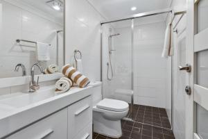 Un baño blanco con inodoro y ducha. en Garigal Studio 1br Unit with Pool Access, en Forestville 17 fotos más