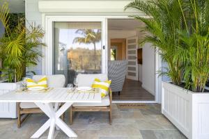 Un porche con una mesa blanca y almohadas amarillas. en Garigal Studio 1br Unit with Pool Access, en Forestville