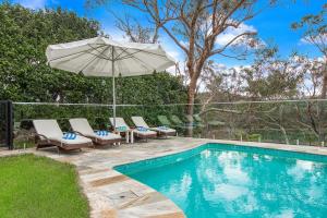 una piscina con tumbonas y sombrilla en Garigal Studio 1br Unit with Pool Access, en Forestville