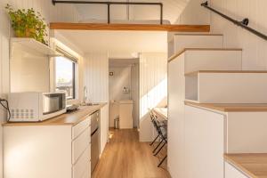 RuatapuにあるRimu View 3 by Tiny Awayのキッチン(白いキャビネット、電子レンジ付きのカウンター付)