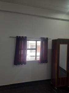 a room with a window with purple curtains and a mirror at DS Villa in Noida