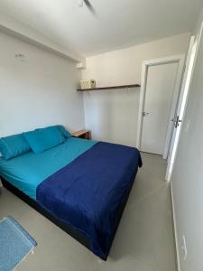 een slaapkamer met een blauw bed in een witte kamer bij Bela Vista in Matinhos