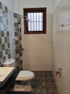 um banheiro com vaso sanitário, pia e janela em Kandy Villa em Kandy