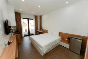 Un dormitorio con una cama blanca y un televisor. en TD Apartment, en Hai Phong