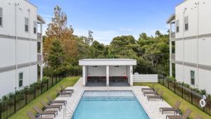 Sea Dweller by AvantStay Rooftop Spa Gulf View Golf Cart Pool في Inlet Beach: مسبح في فناء مبنى سكني مزود بكراسي