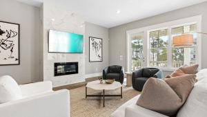 Sea Dweller by AvantStay Rooftop Spa Gulf View Golf Cart Pool في Inlet Beach: غرفة معيشة مع أريكة بيضاء ومدفأة