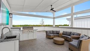 Sea Dweller by AvantStay Rooftop Spa Gulf View Golf Cart Pool في Inlet Beach: مطبخ وغرفة معيشة مع موقد وكراسي