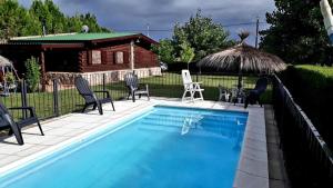 a swimming pool with chairs and a table and an umbrella at Guathemoc cabañas in Panaholma