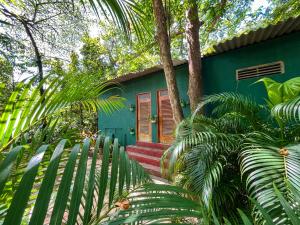 a green house with a red door and palm trees at Silent Bungalow in Udawalawe