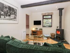 een woonkamer met een groene bank en een open haard bij Corner Cottage in Troutbeck