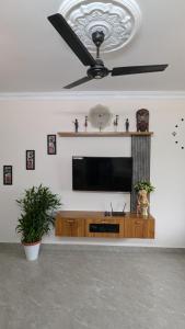 a living room with a television and a ceiling fan at REJOICE Homestay in Kalyānpur