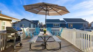 a patio with a grill and an umbrella and a table at Steps to Beach w PatioDeck Foosball Happy Bottom Beach House by AvantStay in Oceano