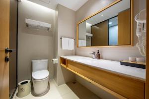 a bathroom with a sink and a toilet and a mirror at JI Hotel Shanghai Changshou Road in Shanghai