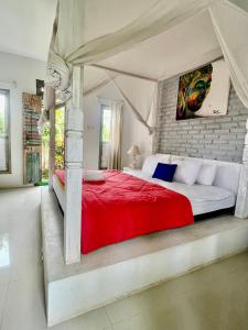 Pranajaya loka villa في تيجاكولا: غرفة نوم بها سرير كبير وبطانية حمراء