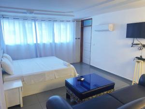 una camera da letto con un letto, un divano e un tavolo di Hôtel Amazone a Cotonou