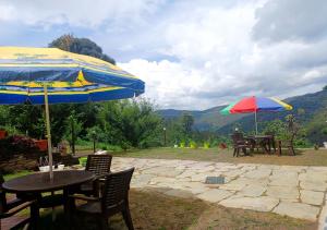 deux tables et chaises avec parasols sur une terrasse dans l'établissement A Home Above the Clouds Riturain Mukteshwar, à Mukteswar 15 autres photos