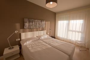 a bedroom with a white bed and a window at Apartamentos Irenaz in Vitoria-Gasteiz
