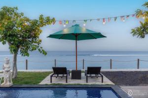 Una mesa y dos sillas bajo una sombrilla junto a una piscina. en La Semaya Beach Villas, en Nusa Penida