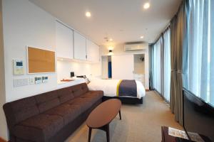 a hotel room with a couch and a bed at 3 Wellness in Okayama