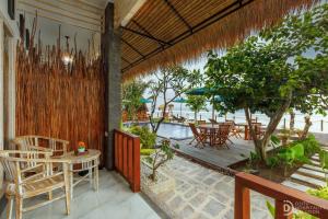 Un patio con mesas y sillas y una piscina. en La Semaya Beach Villas, en Nusa Penida