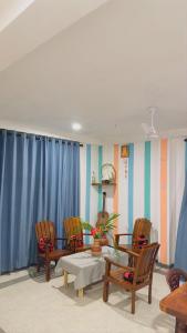 sala de estar con sillas, mesa y cortinas azules en Mabybaby hostel, en Unawatuna