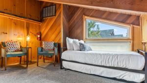 a bedroom with a bed and two chairs and a window at Scenic North Shore Stay w Games Near Snow Summit Lakeview Lodge by AvantStay in Fawnskin