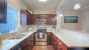 Una cocina con gabinetes de madera y un horno de estufa. en Stylish Condo w Pool Spa Access Wak to Beach Beach Breeze by AvantStay, en Port Aransas
