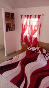 a bedroom with a bed with a red and white blanket at Ecotropicfarmhouse in Cerro Azul