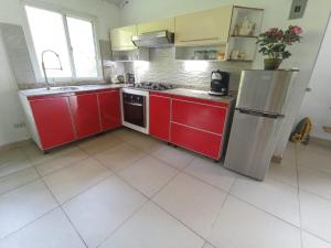 a kitchen with red cabinets and a stainless steel refrigerator at Ecotropicfarmhouse in Cerro Azul