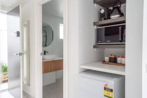 a white kitchen with a microwave and a sink at Bay View Breeze in Lorne