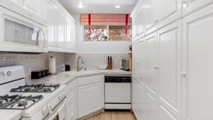 a white kitchen with a stove and a sink at Oceanfront Gem w Balcony Pool Hot Tub Carbon Beach Access Bluewater Haven by AvantStay in Malibu