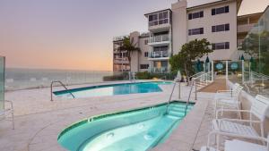 a swimming pool with chairs and a building at Oceanfront Gem w Balcony Pool Hot Tub Carbon Beach Access Bluewater Haven by AvantStay in Malibu