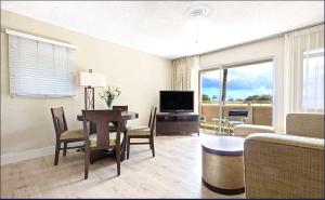 a living room with a dining room table and a television at Plantation Hale on Kauai Steps from the Ocean in Kapaa +12 photos