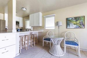 a kitchen with white cabinets and a table and chairs at Plantation Hale on Kauai Steps from the Ocean in Kapaa