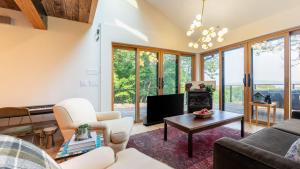 a living room with a couch and a tv at Modern Catskills Escape w Open Living Steam Shower Hot Tub w Mountain Views Minutes from Woodstock Trails Suncliff Vista in Shokan