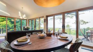a dining room with a wooden table and windows at Modern Catskills Escape w Open Living Steam Shower Hot Tub w Mountain Views Minutes from Woodstock Trails Suncliff Vista in Shokan