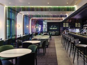 a restaurant with tables and chairs and a bar at Mercure Paris Boulogne in Boulogne-Billancourt