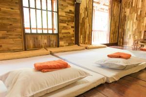 two beds in a room with wooden walls and windows at Minh Quang homestay in Ba Be18